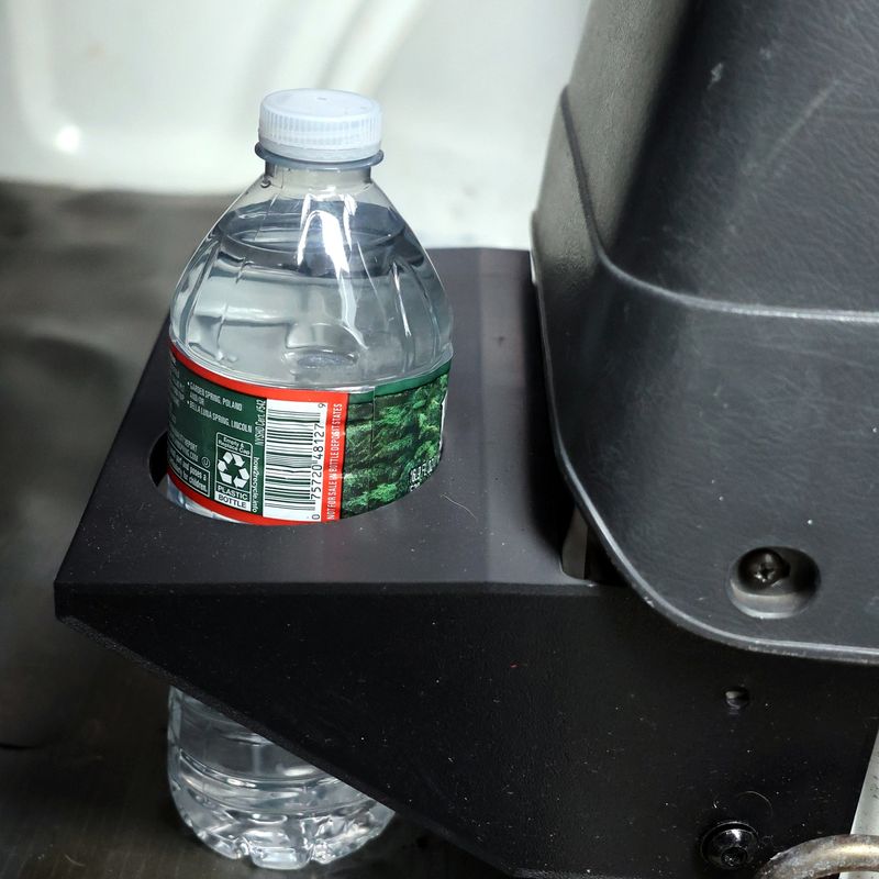 A water bottle sitting in the cup holder, passing through the open bottom